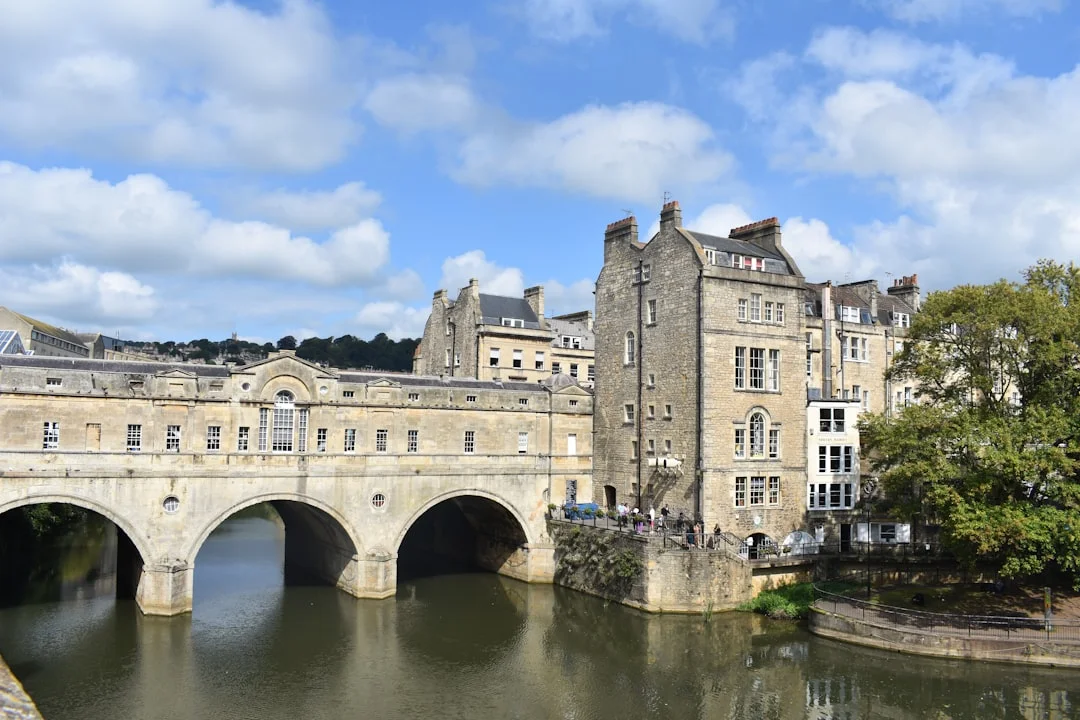 Stone arches of Pulteney Bridge over the River Avon in Bath, with historic buildings and a blue sky