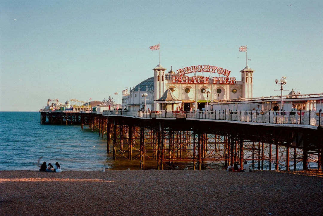 Brighton Palace Pier stretching into the sea at sunset with people sitting on the pebble beach
