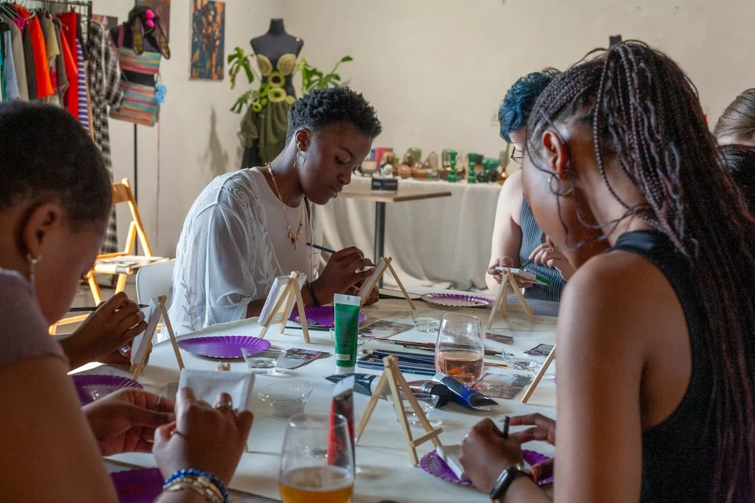 People painting on small canvases at a long table during a creative workshop in Leeds