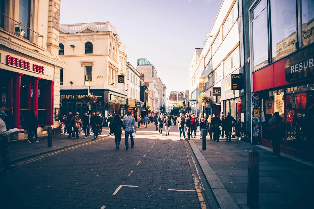 A bustling pedestrian street in Liverpool lined with shops and historic buildings under a clear sky