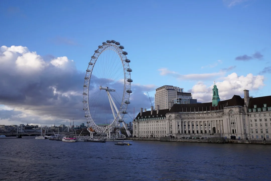 The London Eye and County Hall on the South Bank of the River Thames under a cloudy blue sky
