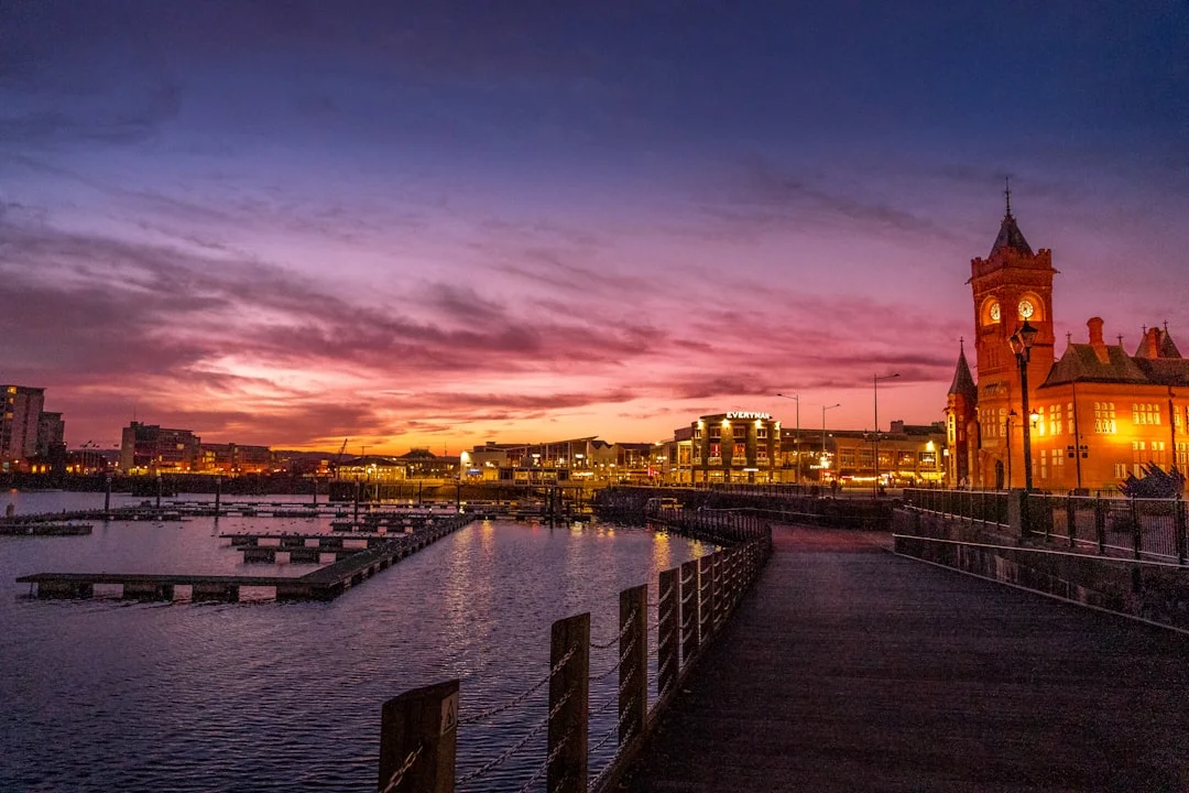 Sunset over Cardiff Bay with the illuminated Pierhead Building and a marina in the foreground