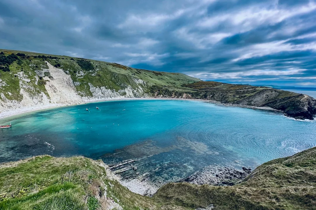 Turquoise waters of Lulworth Cove surrounded by white cliffs and green hills on the Jurassic Coast in Dorset