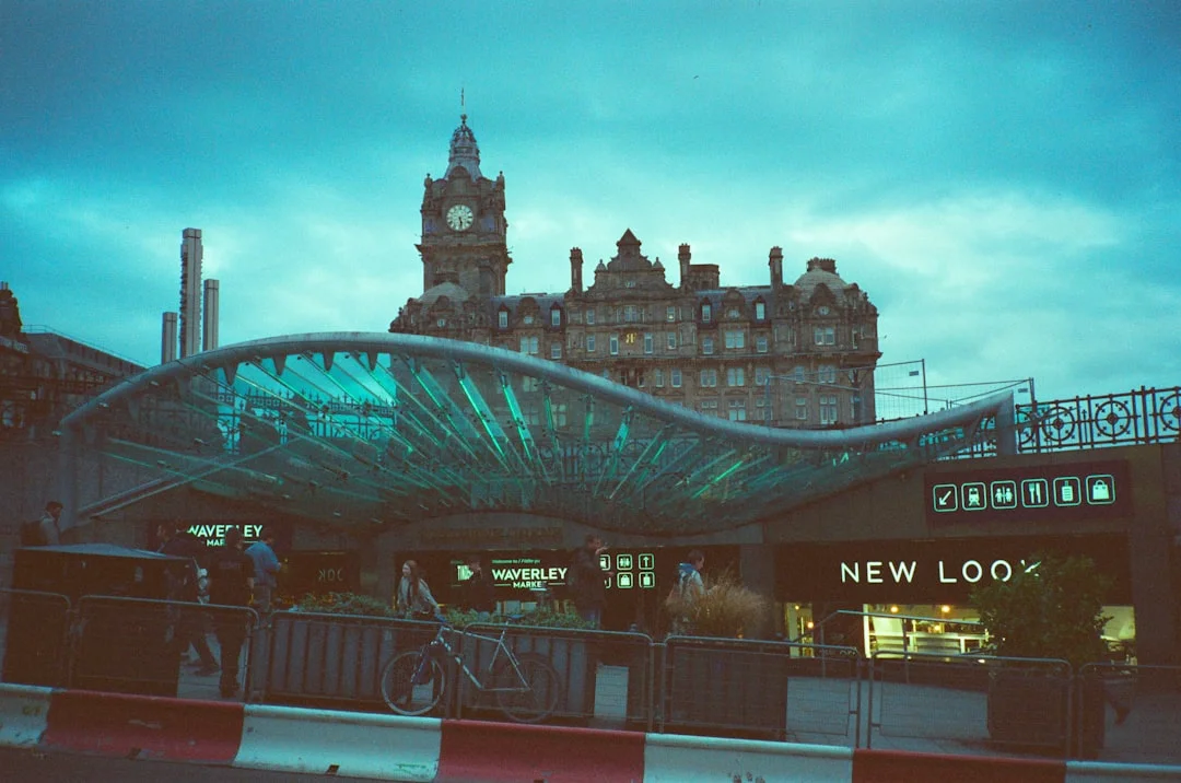 Modern glass canopy entrance to Waverley Market with the historic Balmoral Hotel clock tower in the background
