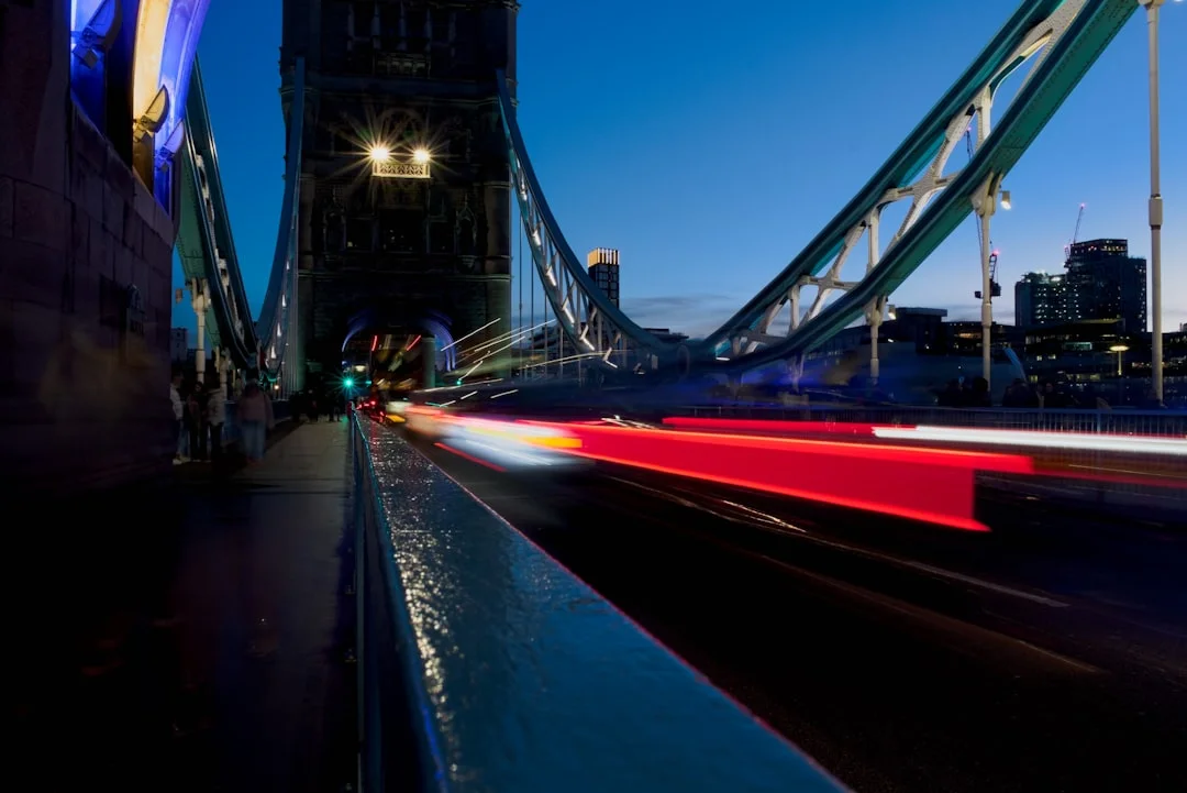 Long-exposure red and white light trails from traffic crossing Tower Bridge in London at night