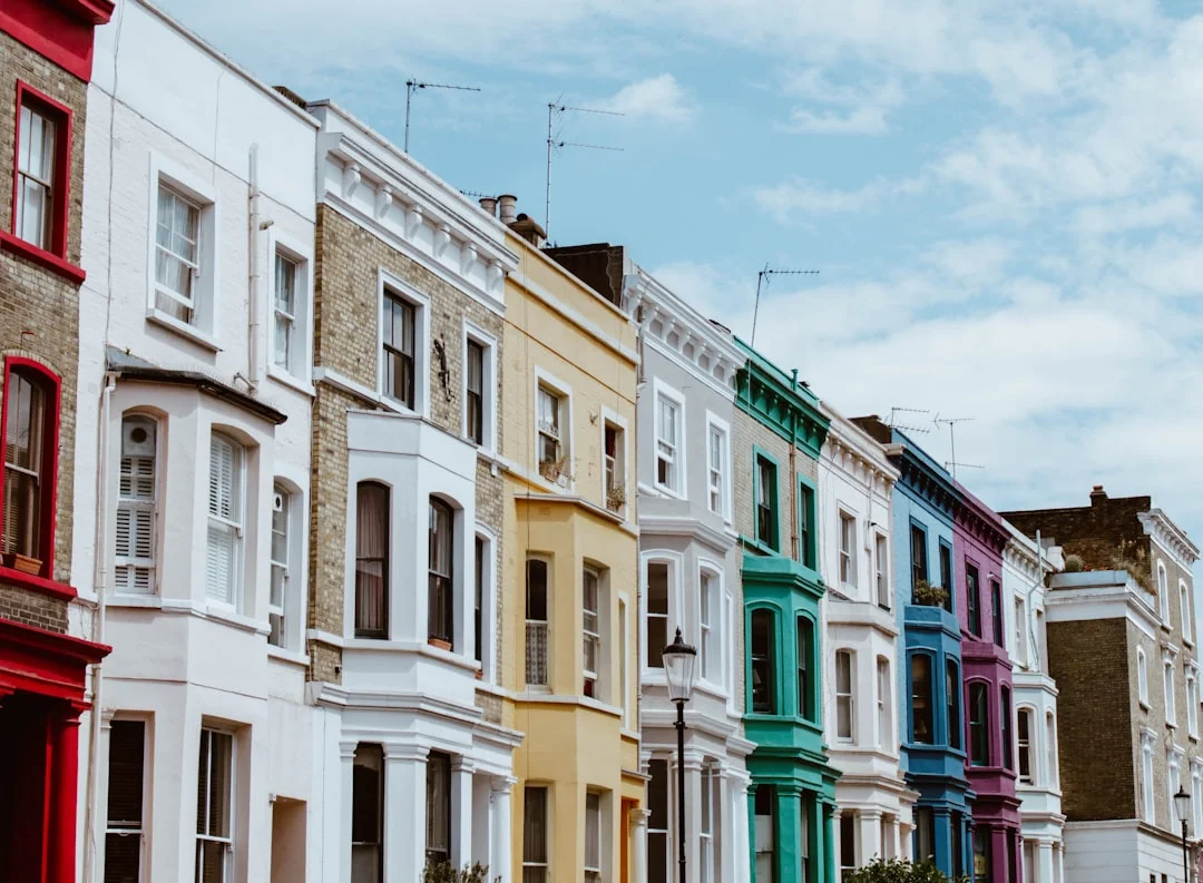 A row of colorful terraced houses in London with white, yellow, green, blue, and purple facades