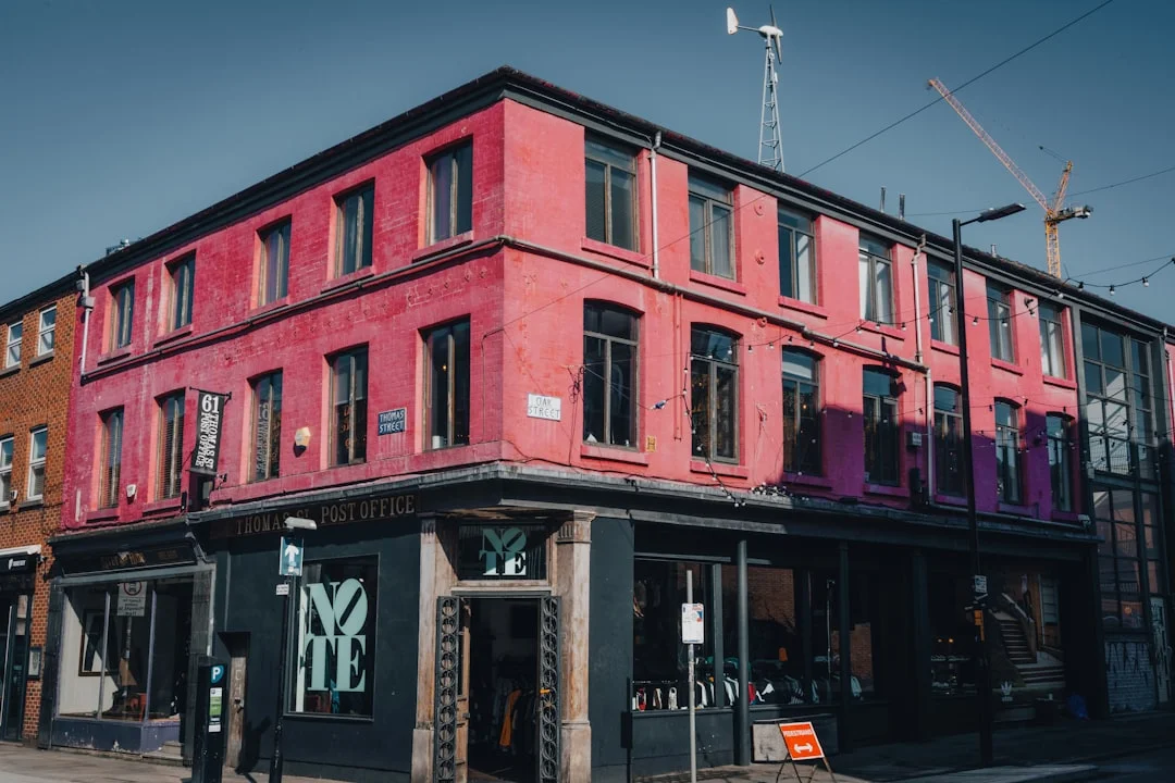 A three-story pink building on a street corner in Manchester's Northern Quarter with a dark storefront
