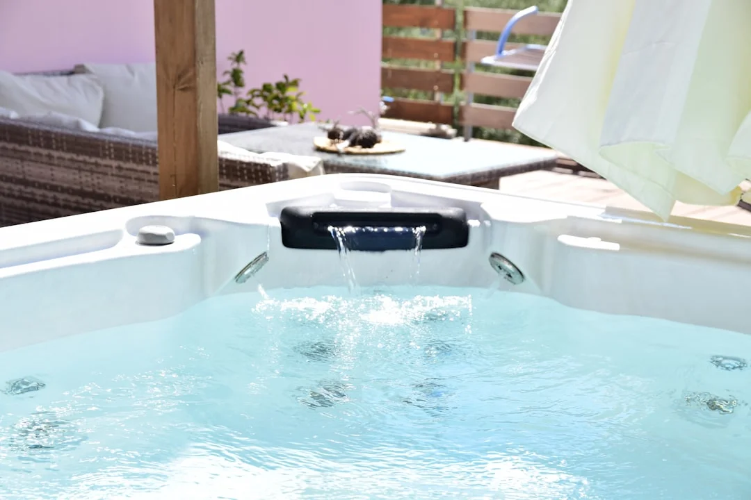 Close-up of a bubbling white hot tub with a waterfall feature on a patio with outdoor furniture