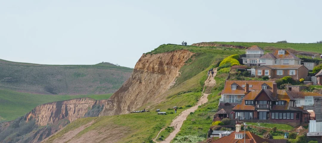 Houses perched on a grassy cliffside overlooking a rugged coastline in Whitby