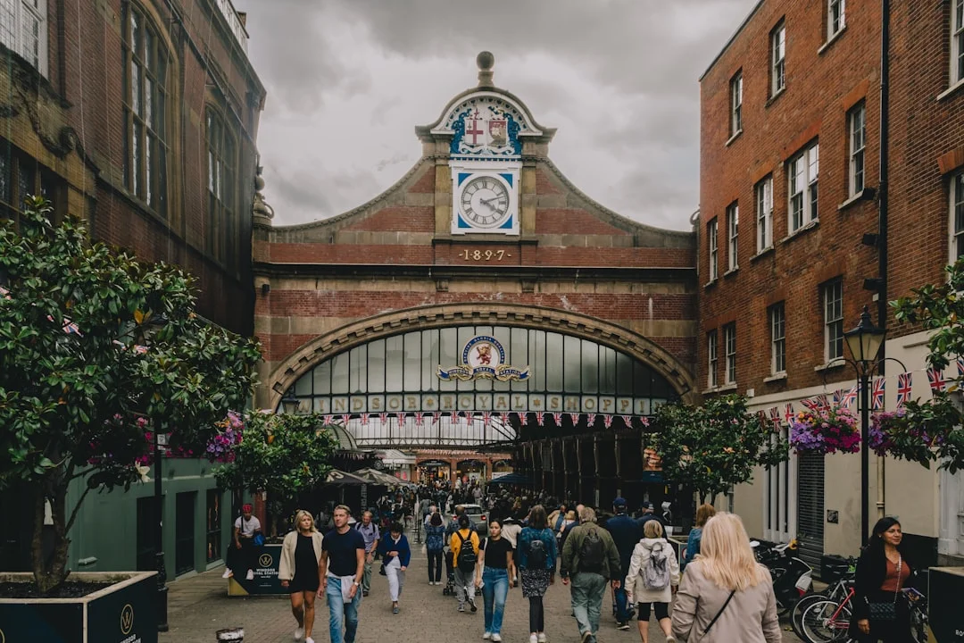 People walking towards the historic Windsor Royal Station archway on a cloudy day