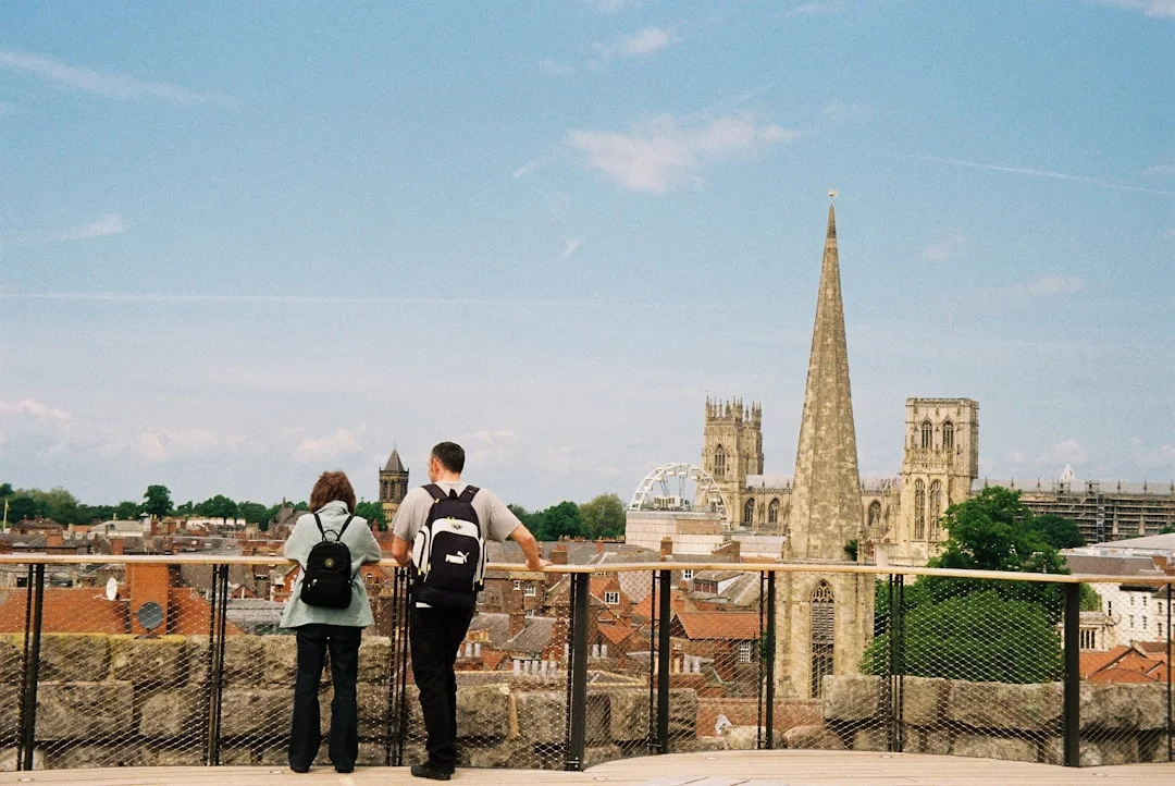 Two people with backpacks look out over the historic city of York and the Minster from the city walls