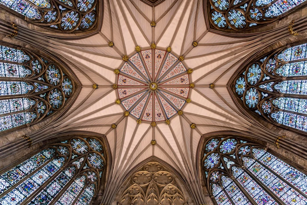 Intricate vaulted star ceiling with radiating ribs and stained glass windows in a Gothic cathedral