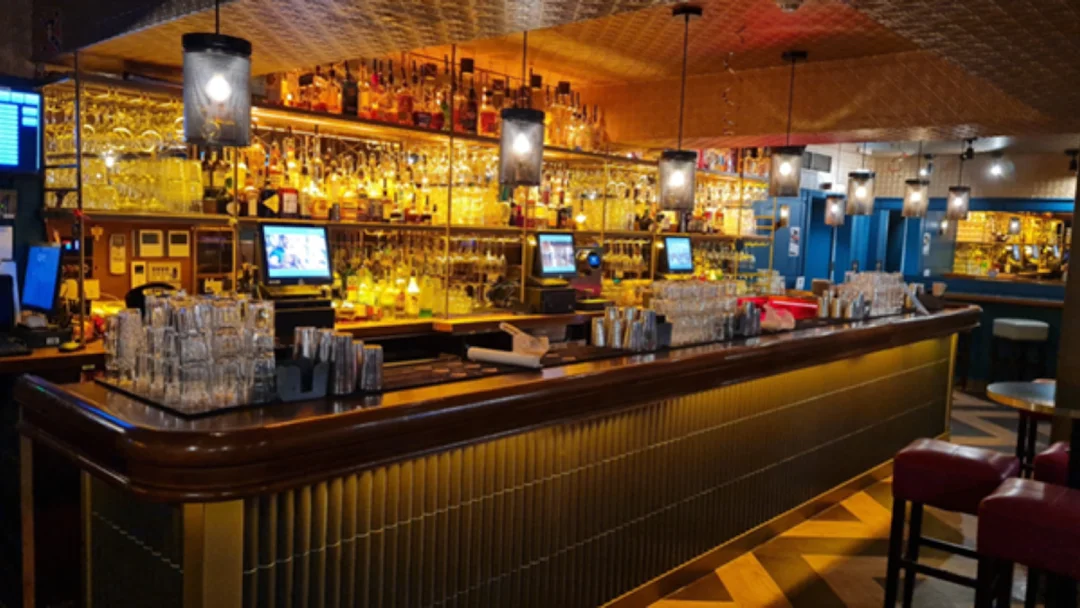 The lively bar area of Be At One in Bournemouth, with bartenders mixing a row of colourful cocktails.