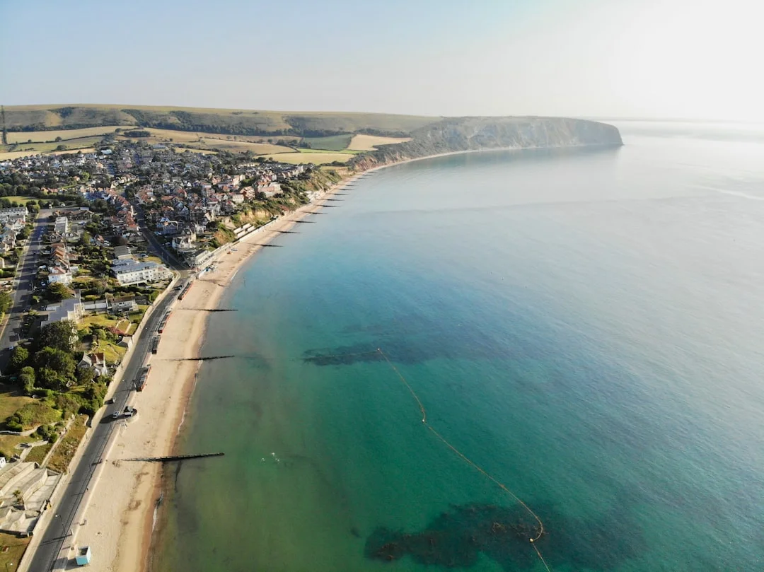 Aerial view of Bournemouth Pier, golden sandy beach, and coastal town beside the clear turquoise sea