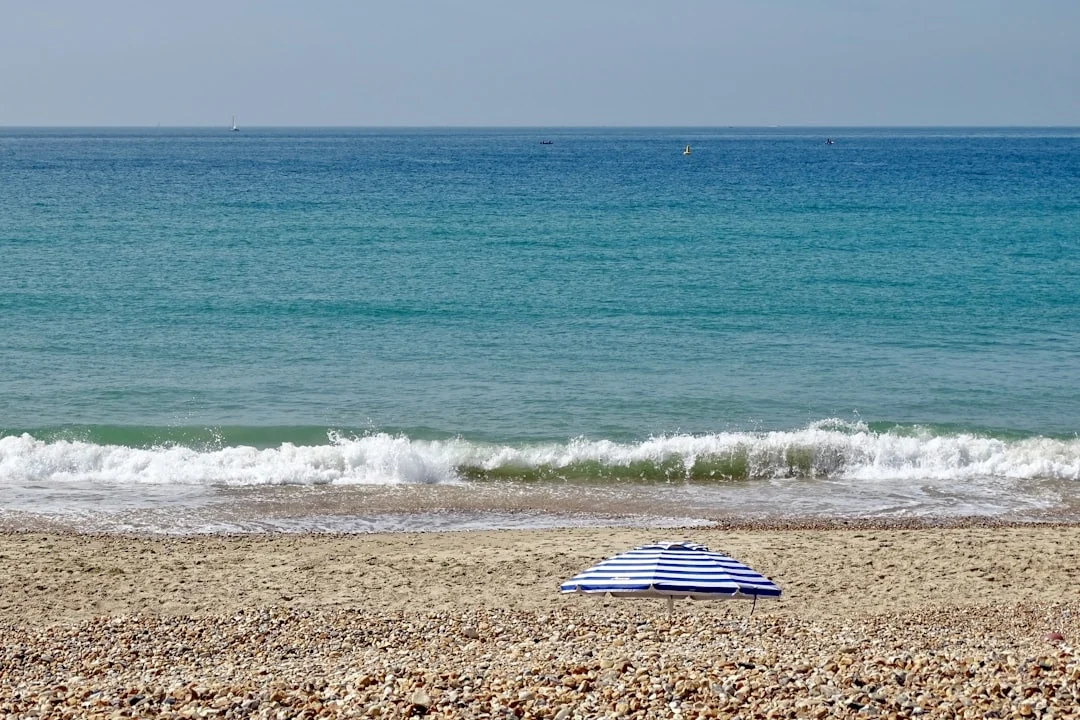 Bournemouth pebbled beach with a folded blue and white striped beach chair, turquoise sea, and breaking waves