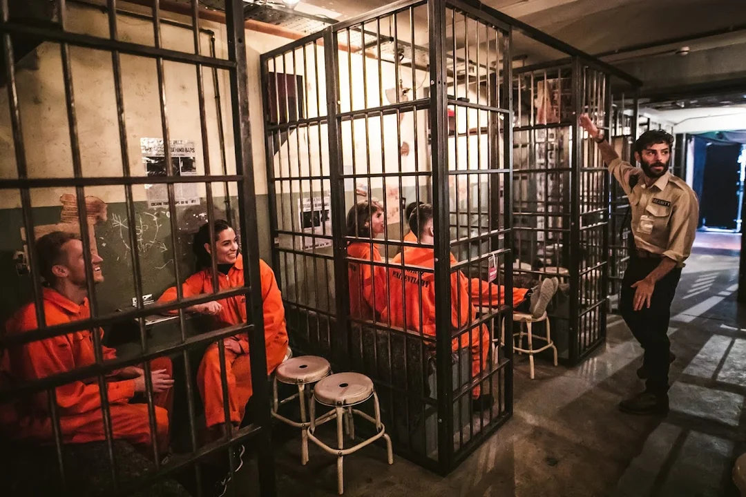 A group dressed in orange jumpsuits inside a prison cell-themed bar at Alcotraz Brighton.