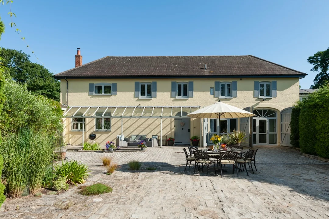 Large yellow Brighton hen party house with blue shutters, outdoor dining area, and patio