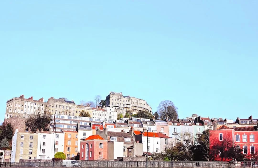 Bristol cityscape featuring colorful terraced houses and grand buildings on a hillside overlooking water
