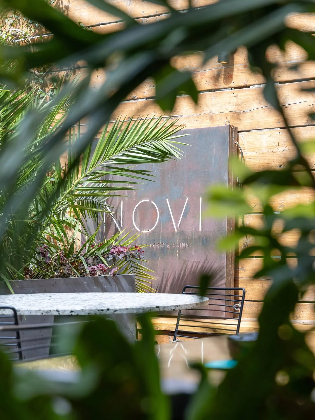 The stylish interior or rooftop terrace of Novi bar in Cambridge, with people enjoying cocktails.
