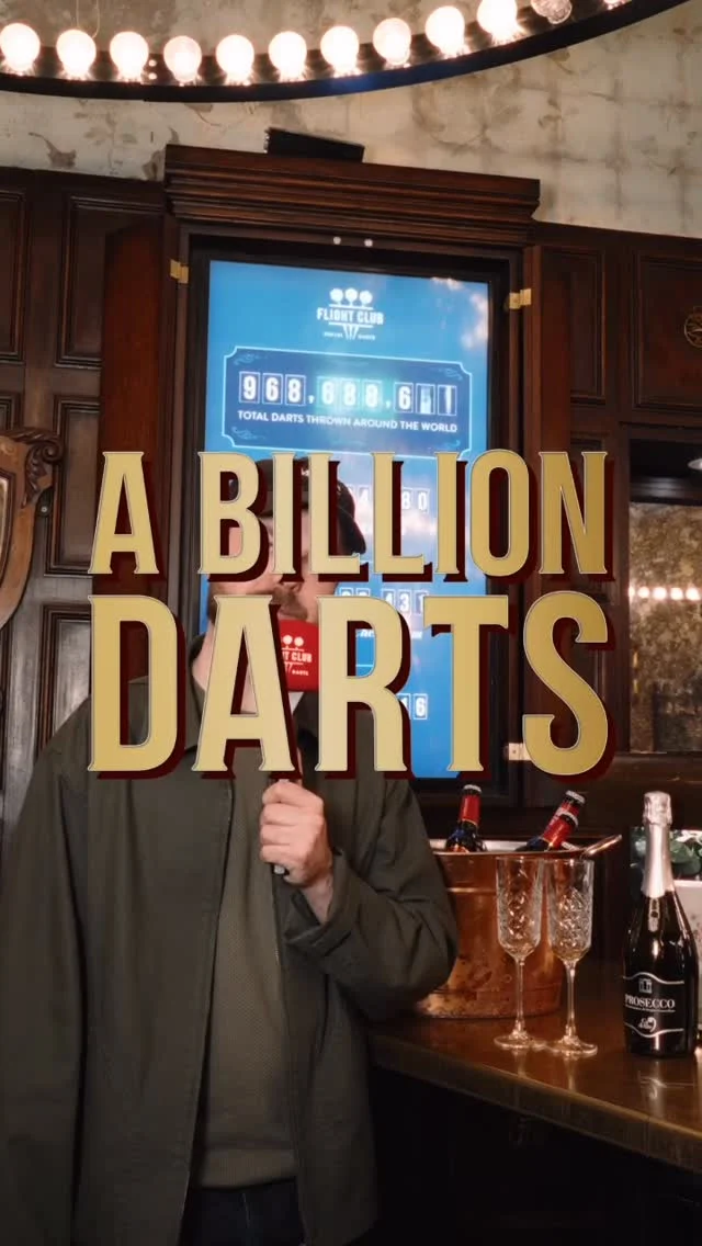 A group of friends playing social darts in a vibrant, stylish booth at Flight Club Cardiff.