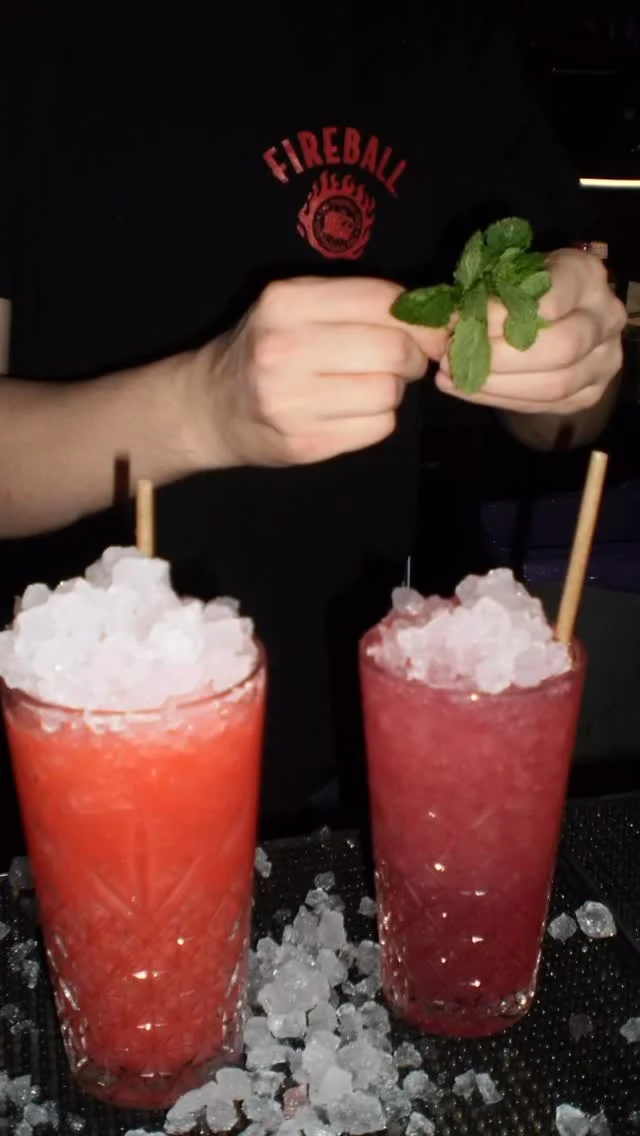 The lively interior of The Cocktail Club in Cardiff, with bartenders mixing drinks.
