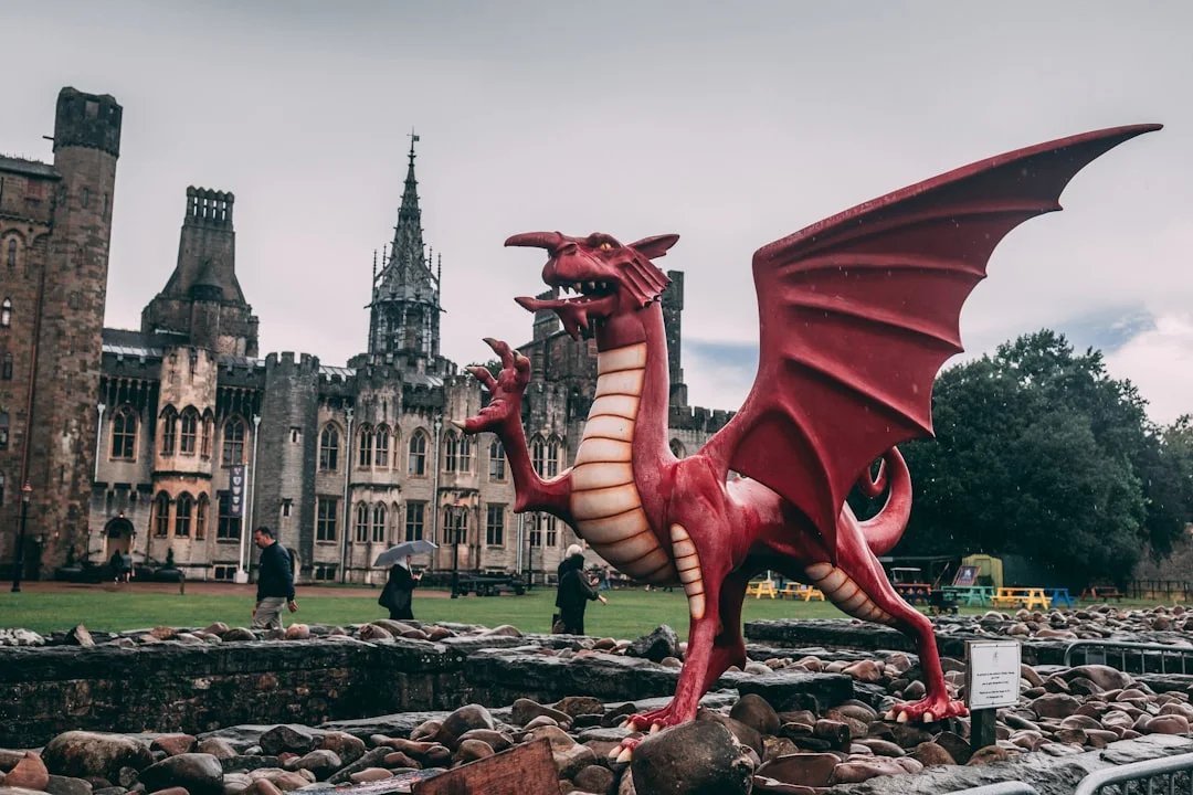 Iconic red Welsh dragon statue with Cardiff Castle towering in the background