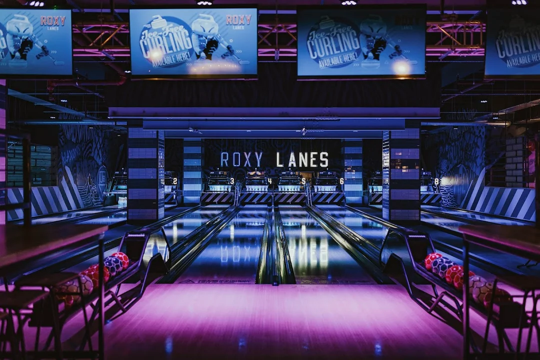 A group playing bowling at Roxy Lanes in Edinburgh, with neon lights and cocktails.