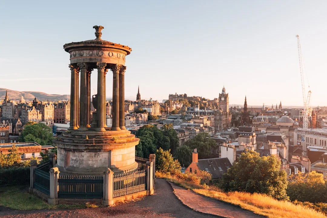 Dugald Stewart Monument on Calton Hill overlooking Edinburgh city skyline and castle at golden hour