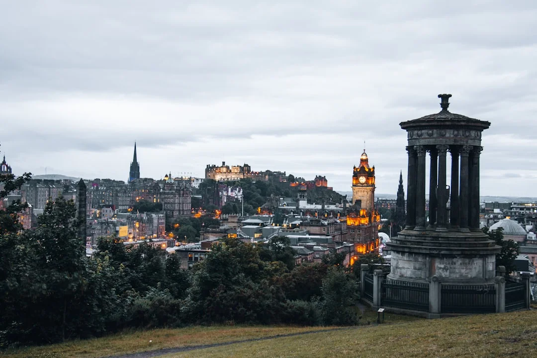 Dusk view of Edinburgh from Calton Hill, with the Dugald Stewart Monument, Balmoral clock tower, and Edinburgh Castle