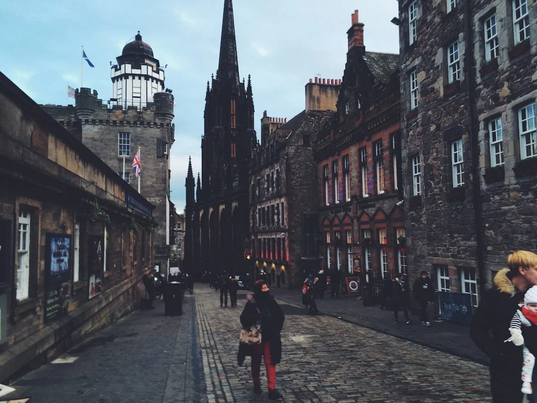 Edinburgh Royal Mile at dusk with historic stone buildings, church spire, and pedestrians