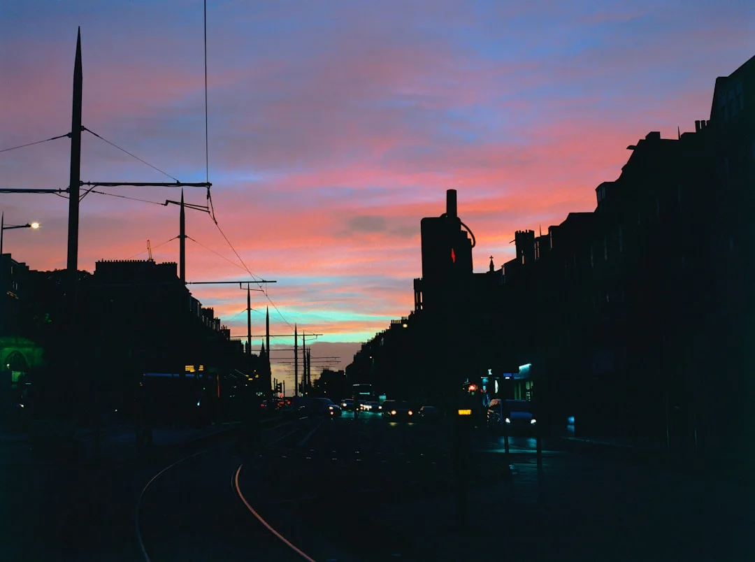 Edinburgh tram tracks curving through a city street at sunset with colourful sky