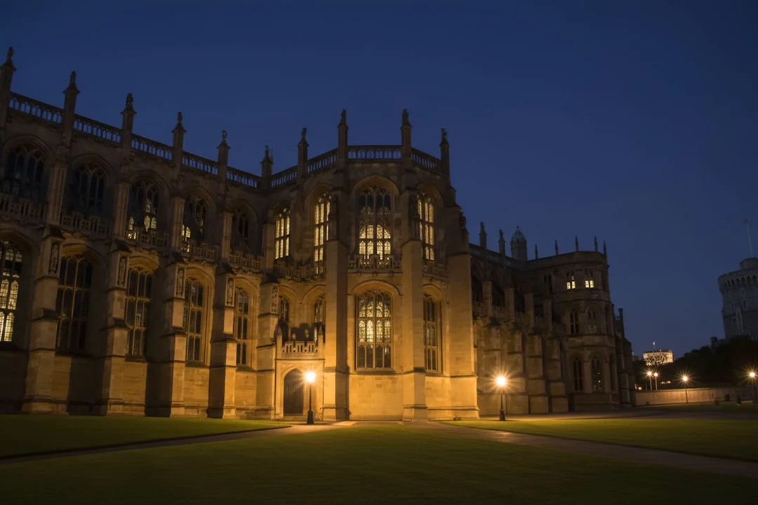 Illuminated Gothic architecture of Windsor Castle at night against a deep blue evening sky