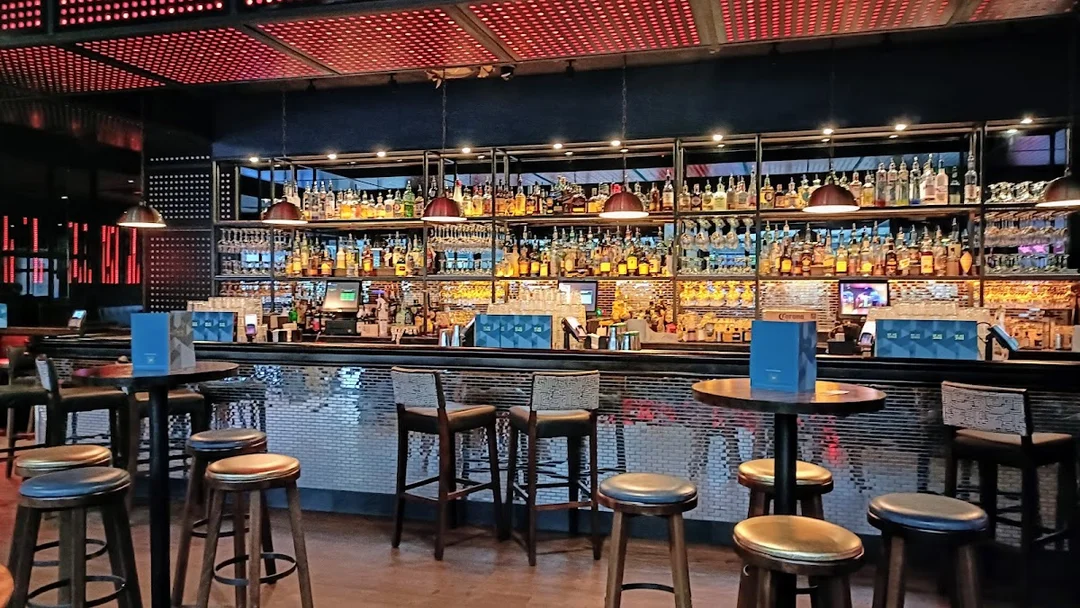 A group of friends laughing and shaking cocktails during a masterclass at Be At One bar.