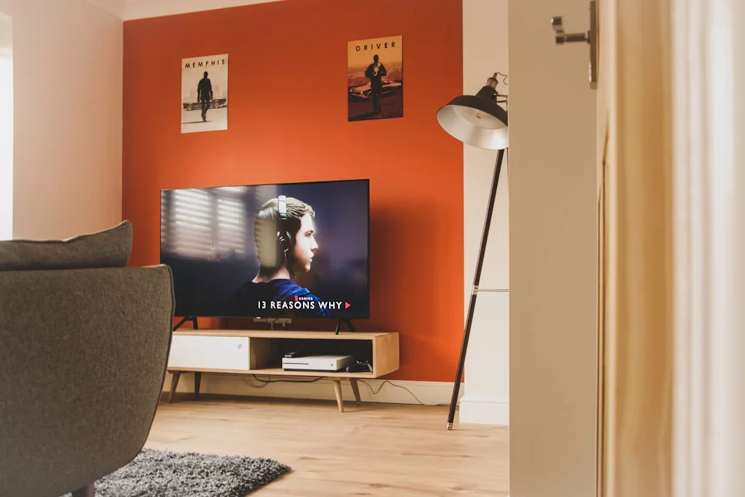 Stylish Liverpool hen party apartment living room with TV, comfy sofa, orange wall, and modern decor