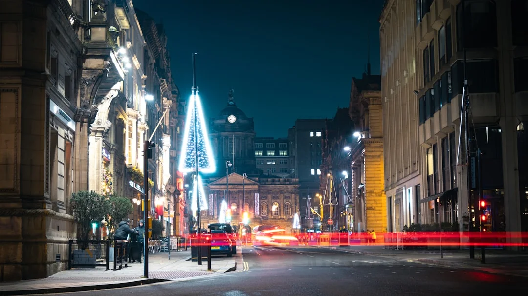 Vibrant Liverpool street at night, featuring festive lights, historic architecture, and car light trails