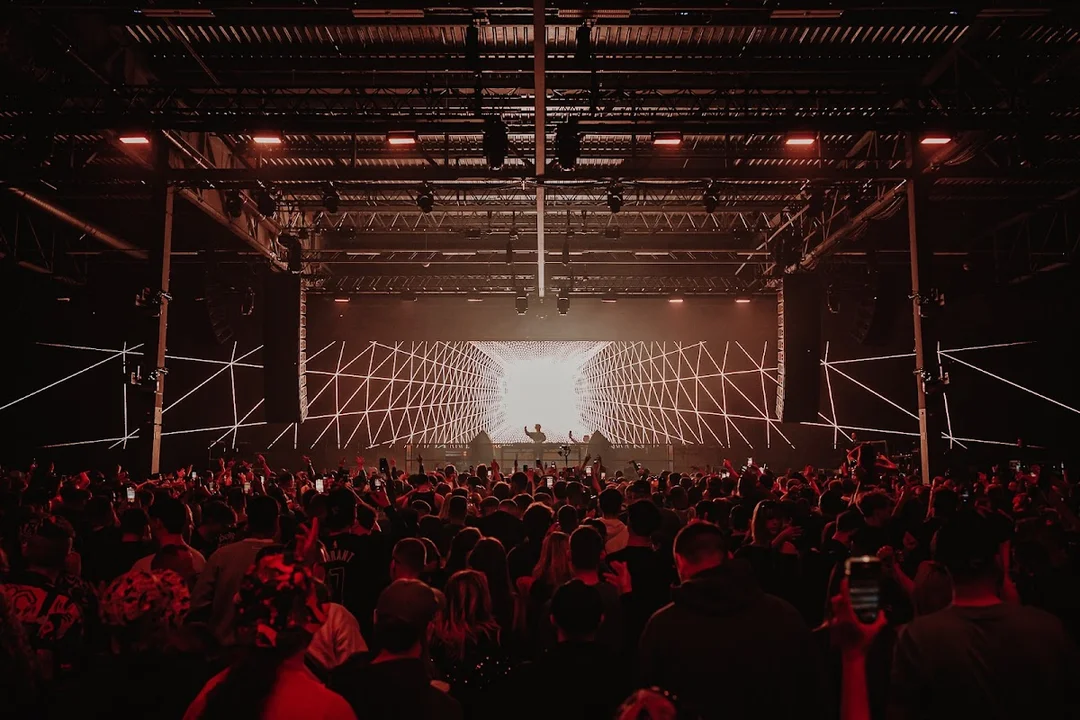 A large crowd dancing under impressive light rigs at the Drumsheds nightclub in London.