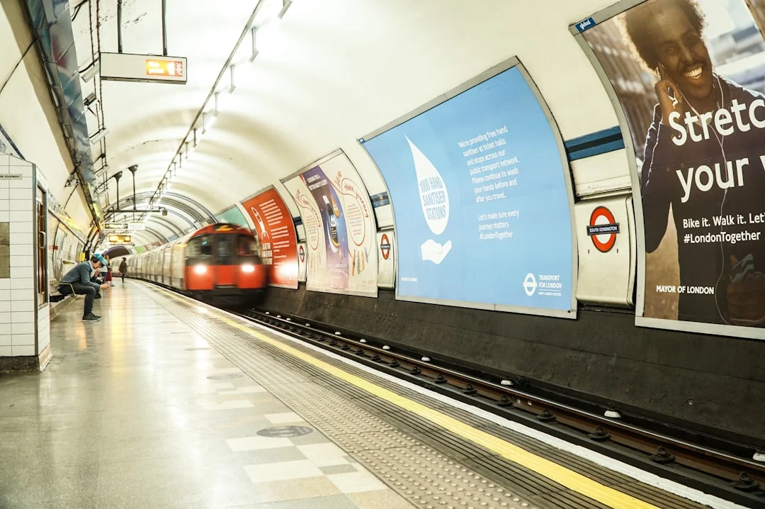 A red tube train pulls into South Kensington station, with posters lining the curved tunnel walls