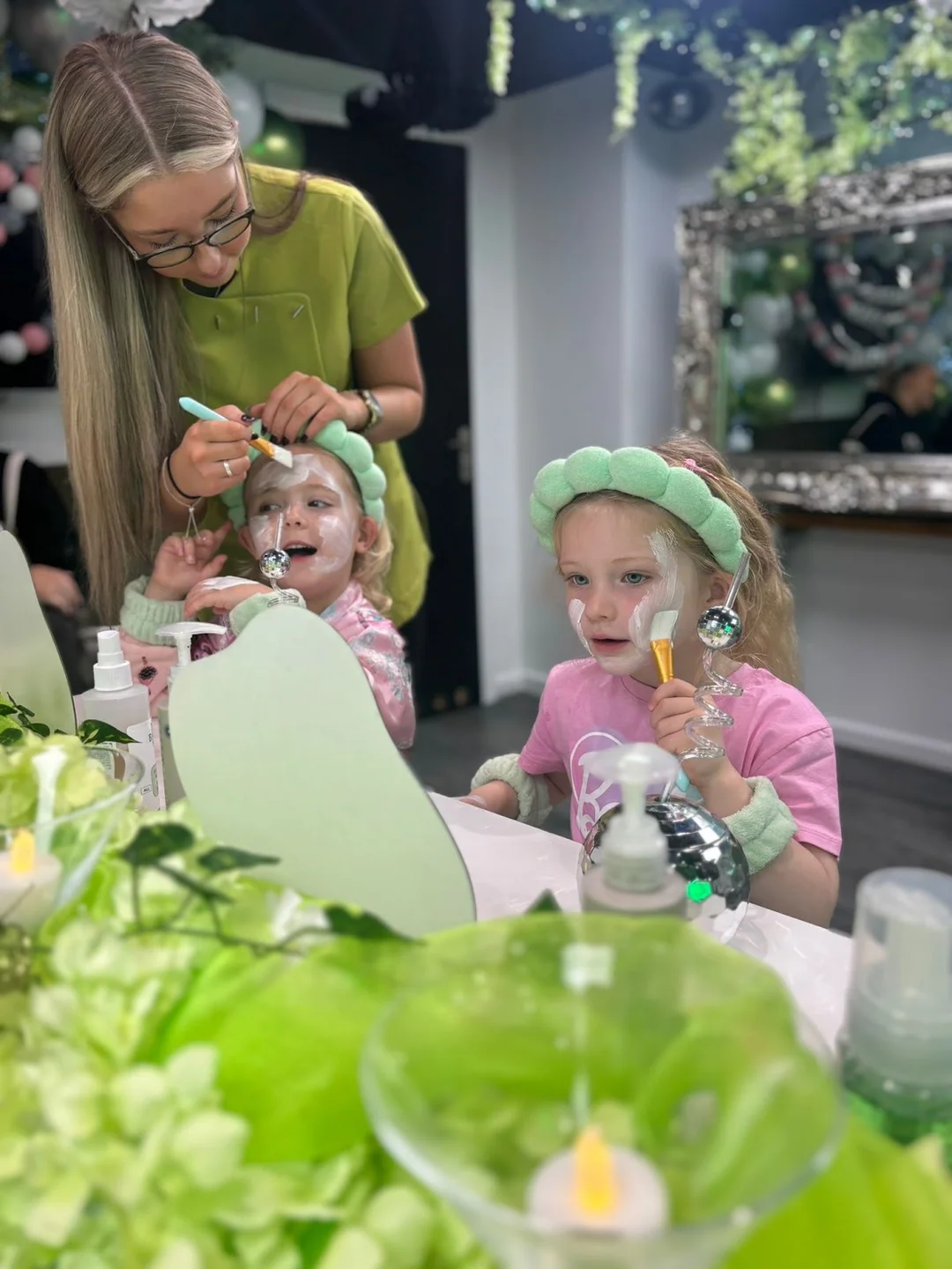 A mobile beauty therapist giving a manicure to a guest during a hen party pamper session at home.