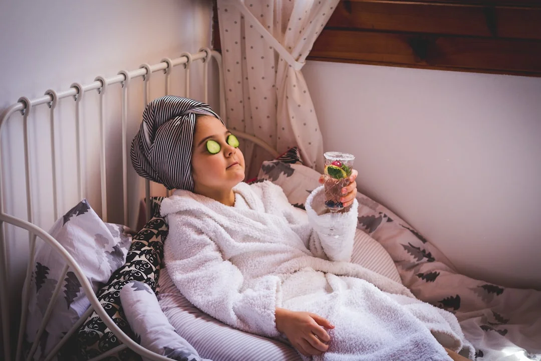 Young girl relaxing at a Manchester mobile pamper party, wearing a robe, head towel, cucumber eyes, holding a drink