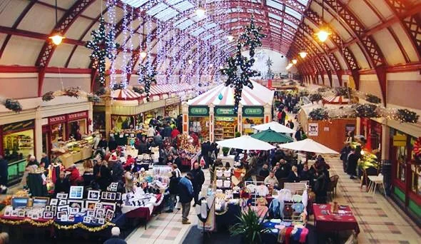 The historic arched interior of Grainger Market in Newcastle, bustling with shoppers and stalls.