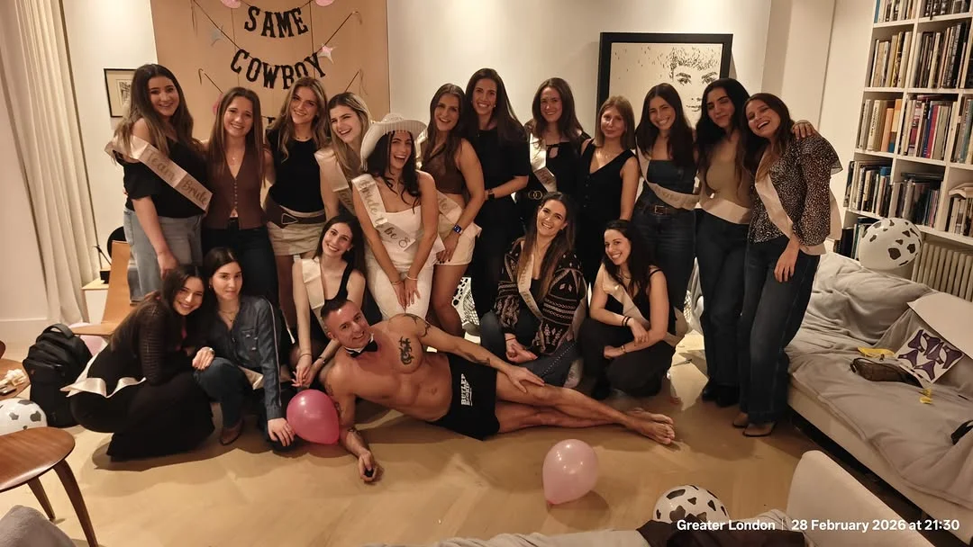 A buff butler serving cocktails to a group of women at a hen party.