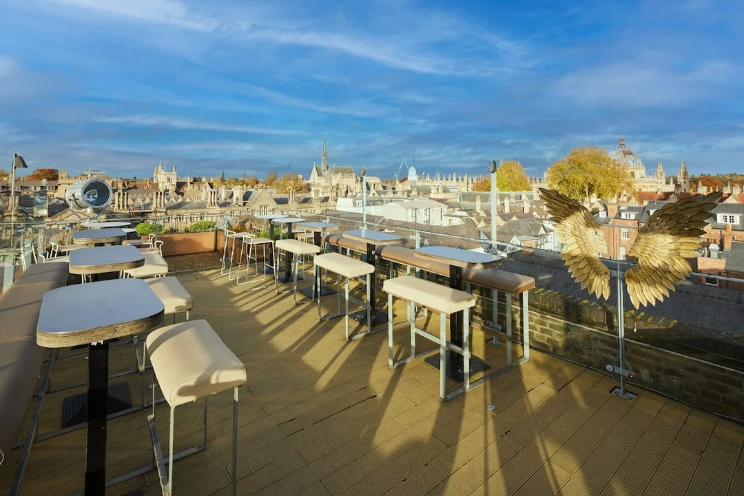 A group of friends enjoying cocktails on the rooftop terrace of The Varsity Club, with Oxford