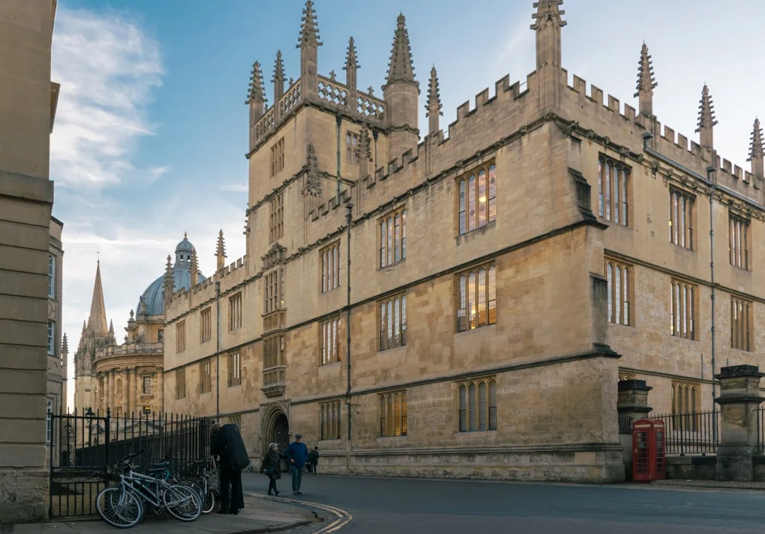 Historic stone facade of the Bodleian Library in Oxford with spires and a dome in the distance