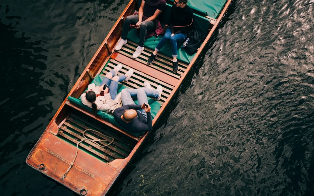 Overhead view of people relaxing on a wooden punt boat on a river in Oxford
