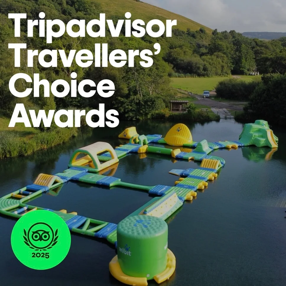 A group of friends tackling the inflatable water obstacle course at Dorset Adventure Park.