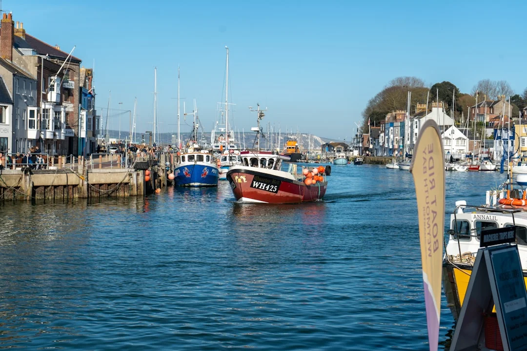Fishing boats and yachts in Weymouth harbour, surrounded by colourful buildings under a clear blue sky