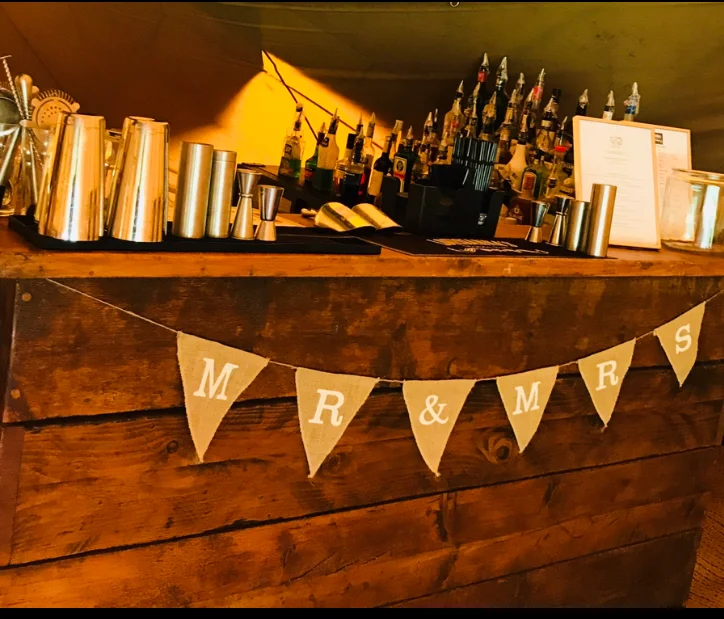 A group of friends laughing while a mixologist teaches them to make cocktails in a private house.