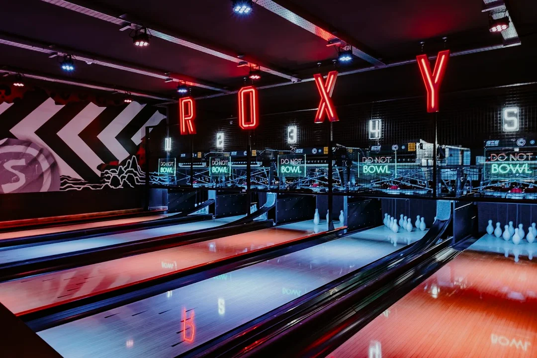 A group of friends playing beer pong or shuffleboard at a Roxy Ball Room venue.